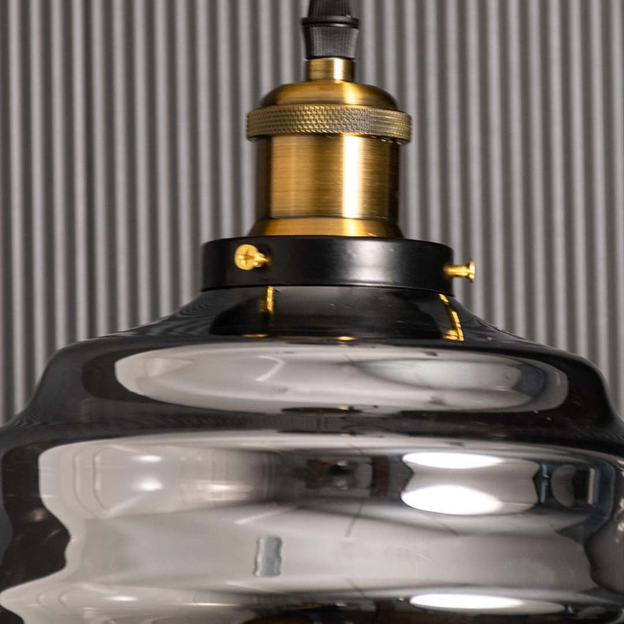 Detailed closeup of the rippled smoked glass pendant light showing the curved glass texture and brass fitting with subtle reflections enhancing the elegant modern design.