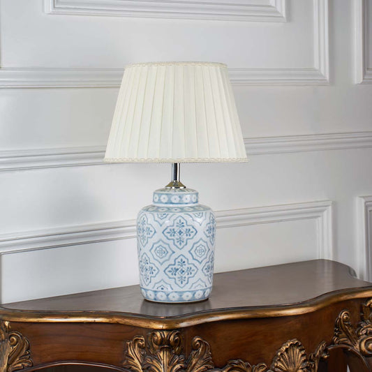 Stylish ceramic table lamp with intricate blue motifs and beige pleated shade turned off on white background showcasing timeless handcrafted appeal.