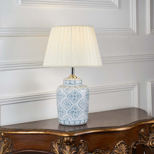 Stylish ceramic table lamp with intricate blue motifs and beige pleated shade turned off on white background showcasing timeless handcrafted appeal.