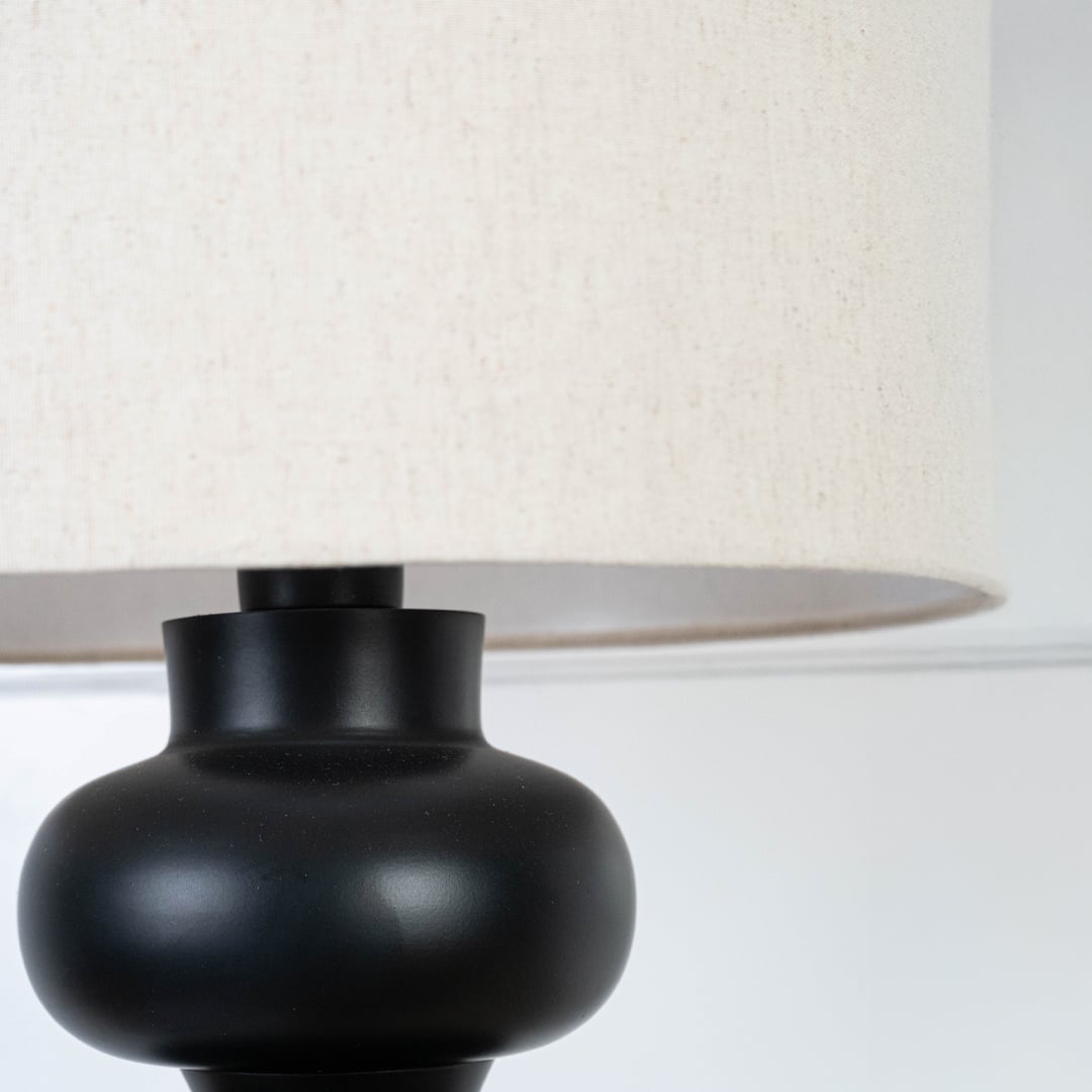 Detailed view of the green ceramic table lamp neck with beige fabric lampshade connection.