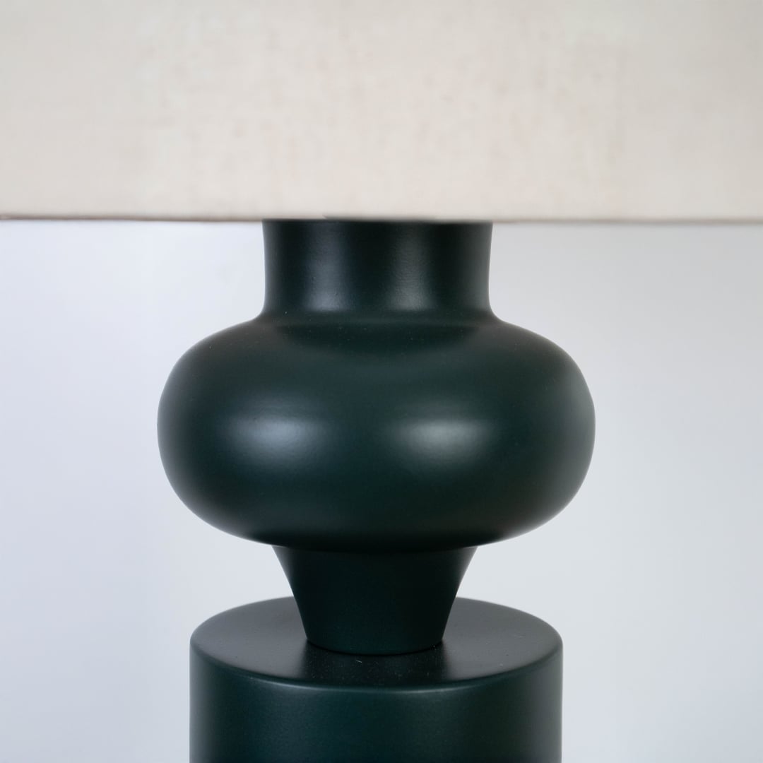 Detailed view of the curved ceramic neck and matte green finish of the table lamp beneath the shade.