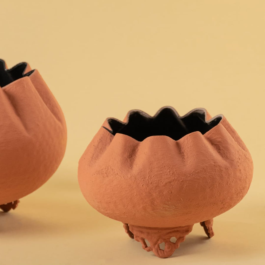 Closeup of terracotta metal scalloped bowl planter showing textured detailing and ornate base perfect for elegant home styling.