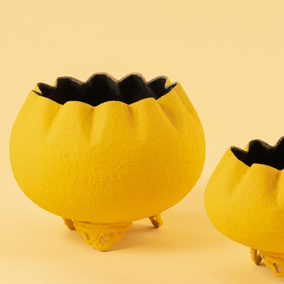 Closeup of yellow metal scalloped bowl planter showing its textured shape and ornate base perfect for stylish home decor.