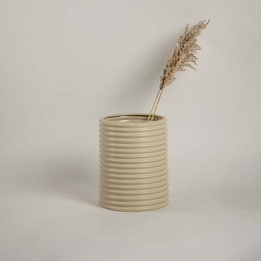 Contemporary beige ceramic vase with ribbed design styled with dried flowers for elegant living space decoration.
