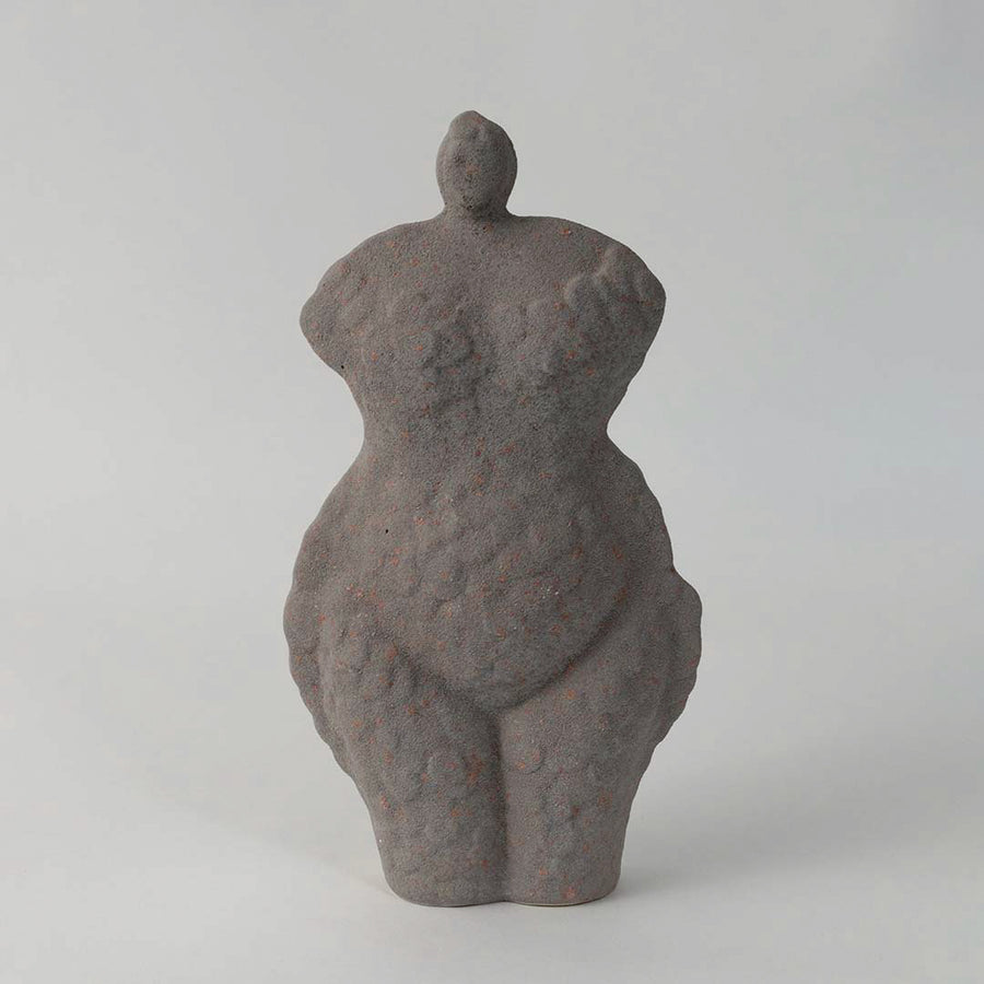 Abstract ceramic torso sculpture with textured grey finish placed on white surface against neutral background showcasing artistic modern home decor accent.