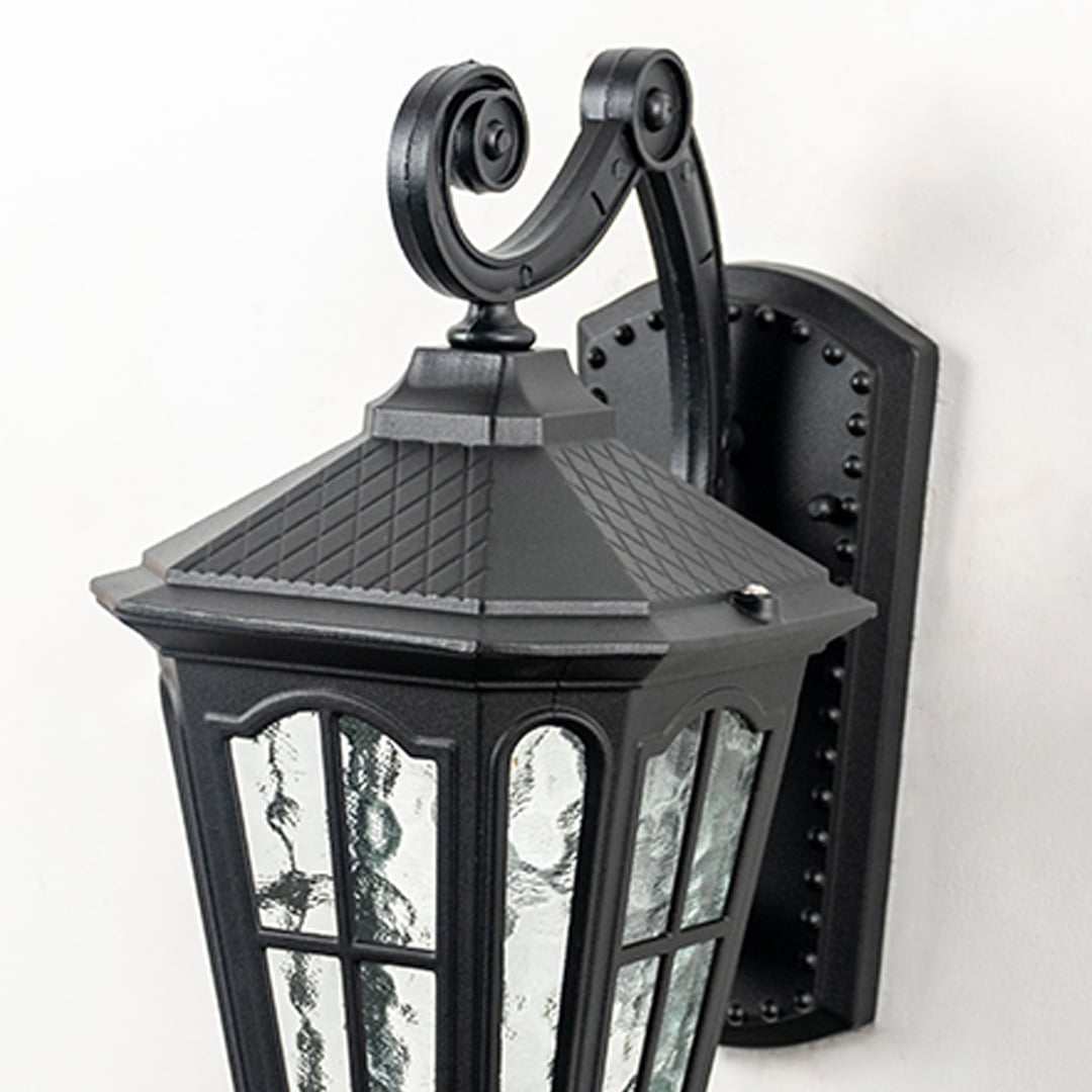 Closeup of traditional black metal outdoor wall lantern showing curved arm glass panels and weather resistant classic lighting design.