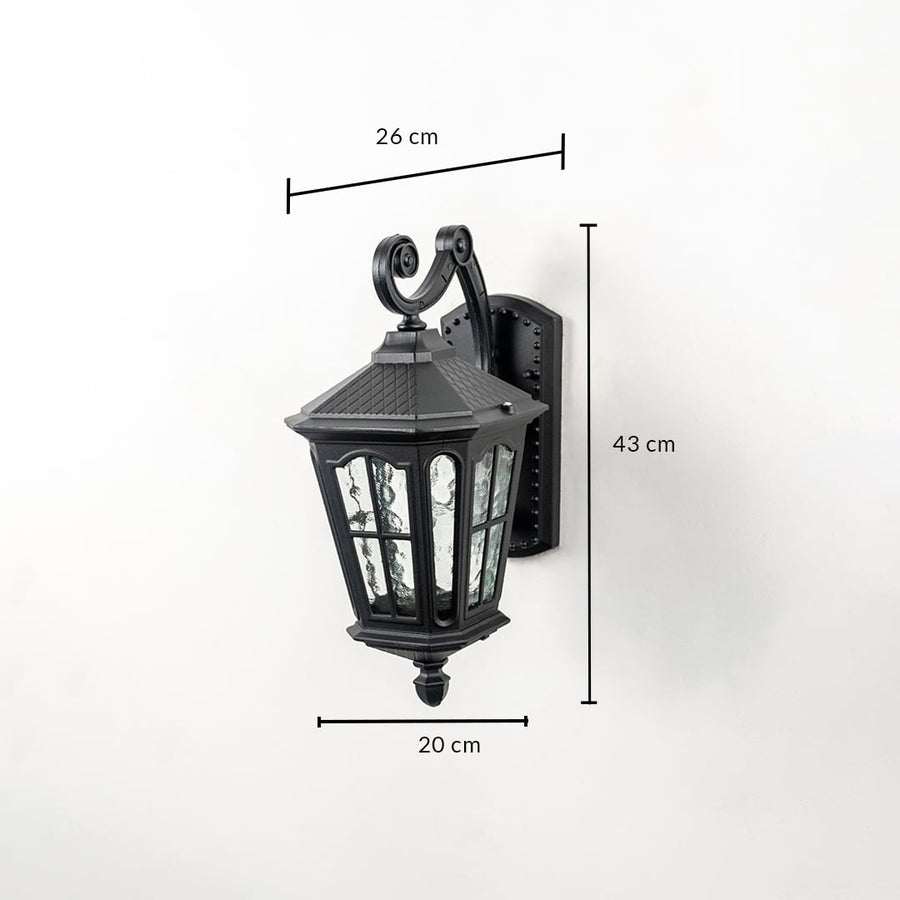 Outdoor wall light with ornate lantern design black frame and glass panels shown with 43 cm height 26 cm width 20 cm depth.