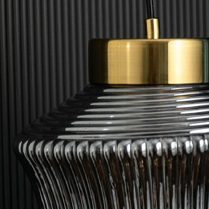 Closeup of ribbed smoked glass pendant light capturing its textured curved surface brass top detail and modern reflective finish for stylish decor.