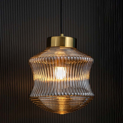 Smoked ribbed glass pendant light displayed with light on against a dark backdrop enhancing its warm illumination and decorative modern form.