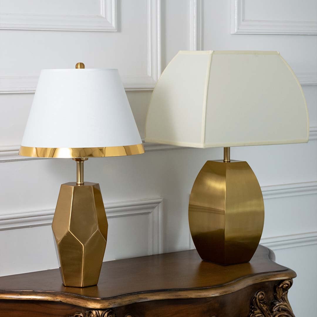 Gold faceted table lamps with white tapered shades shown together with lights off highlighting elegant geometric bases for modern home styling.