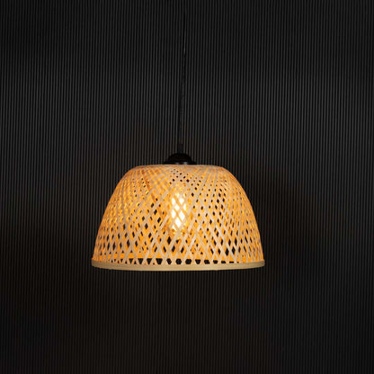 Woven bamboo pendant light glowing on black background with natural dome wicker shade for bohemian interior decor.