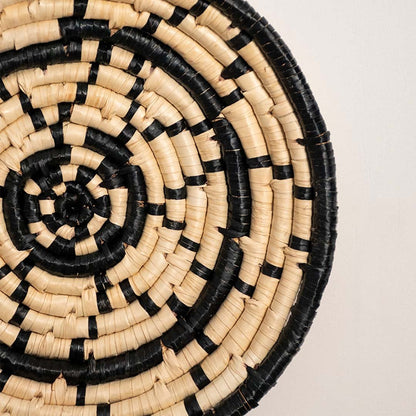 Detailed closeup view of the tight coil weaving and black wrapped sections on the natural seagrass wall basket surface quality.