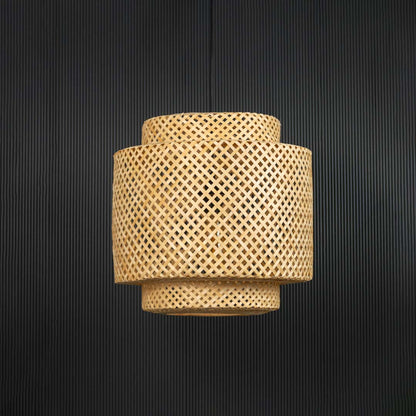 Layered rattan pendant light with handwoven bamboo shade in natural finish turned off against black background.