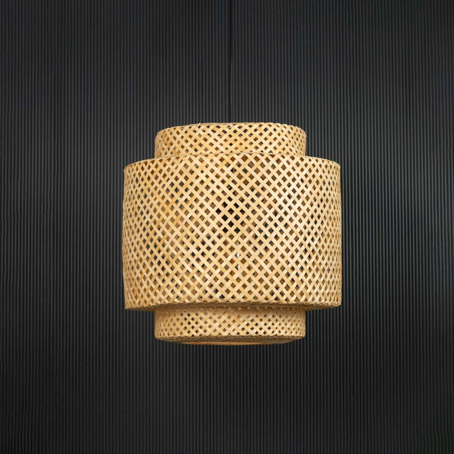 Layered rattan pendant light with handwoven bamboo shade in natural finish turned off against black background.