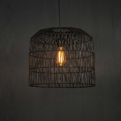 Black handcrafted wire pendant lamp glowing on dark background radiating a soft warm light through intricate geometric weave.