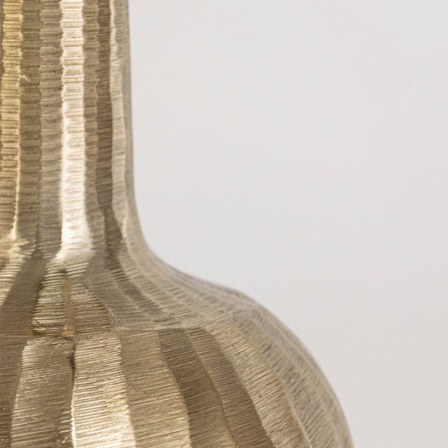 Close view of gold vase showing hammered ribbed base and smooth tapered neck in sculptural metallic finish