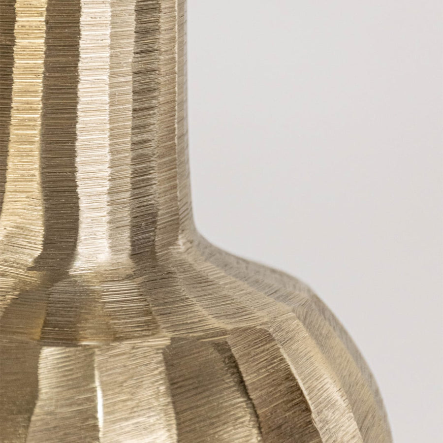 Closeup of gold vase showing smooth hammered neck and ribbed metallic base in elegant sculptural form
