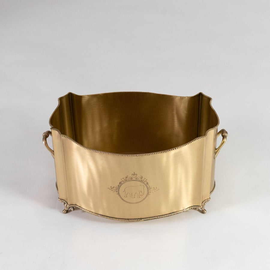 Closeup of gold metal planter on white background highlighting curved shape and smooth metallic finish with handle.