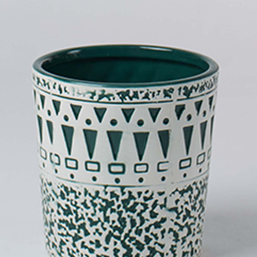 A close view of a ceramic planter with teal geometric and speckled patterns showing detailed craftsmanship and a smooth glossy interior finish.