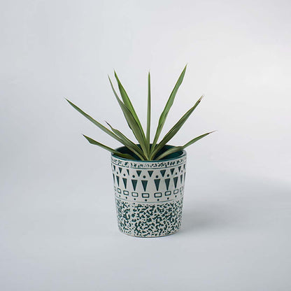 A patterned teal and white ceramic planter showcased in a bright minimal scene emphasizing its textured design and stylish handcrafted appeal.
