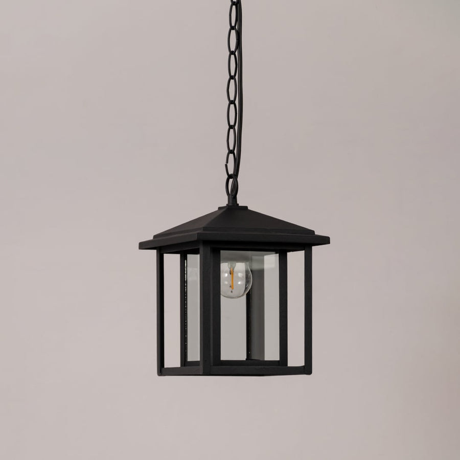 Black metal outdoor hanging lantern with clear glass panels shown unlit on a white background for product clarity.