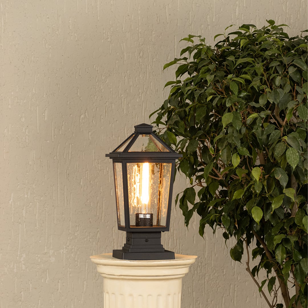 Black metal outdoor post lantern with light on Warm ambient lighting on a decorative pillar Main Lifestyle image.