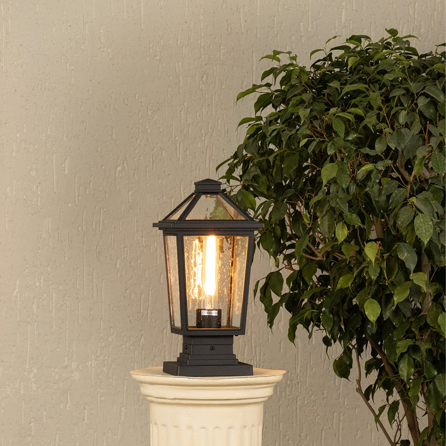 Black metal outdoor post lantern with light on Warm ambient lighting on a decorative pillar Main Lifestyle image.