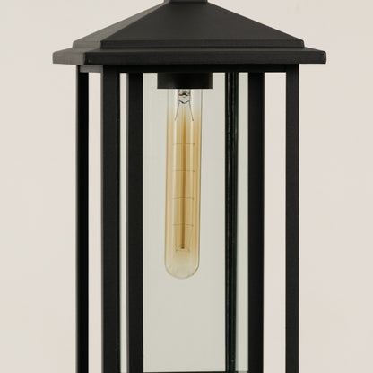 Closeup of black metal outdoor lantern with clear glass panels and bulb on white background perfect for modern exterior decor lighting.