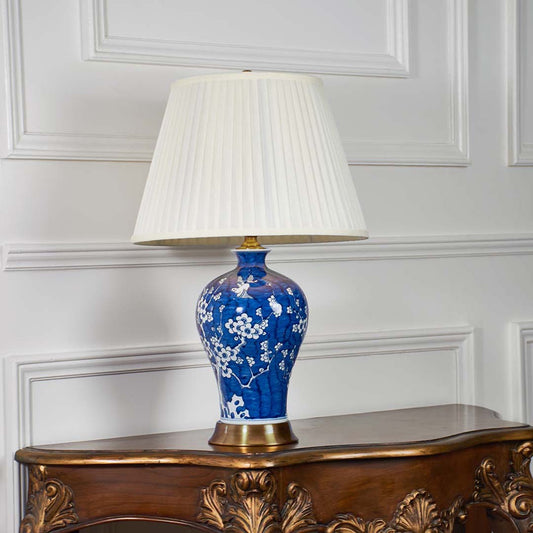 Traditional blue ceramic lamp with detailed floral pattern and cream shade displayed on a white background for timeless decor appeal.