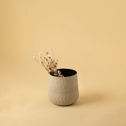 Small cream textured pot with black interior styled in a cozy modern space adding soft minimal decor to shelves and tables.