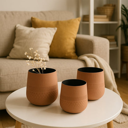 Terracotta textured pot with black interior styled with matching decor pieces creating a warm earthy modern lifestyle setting.