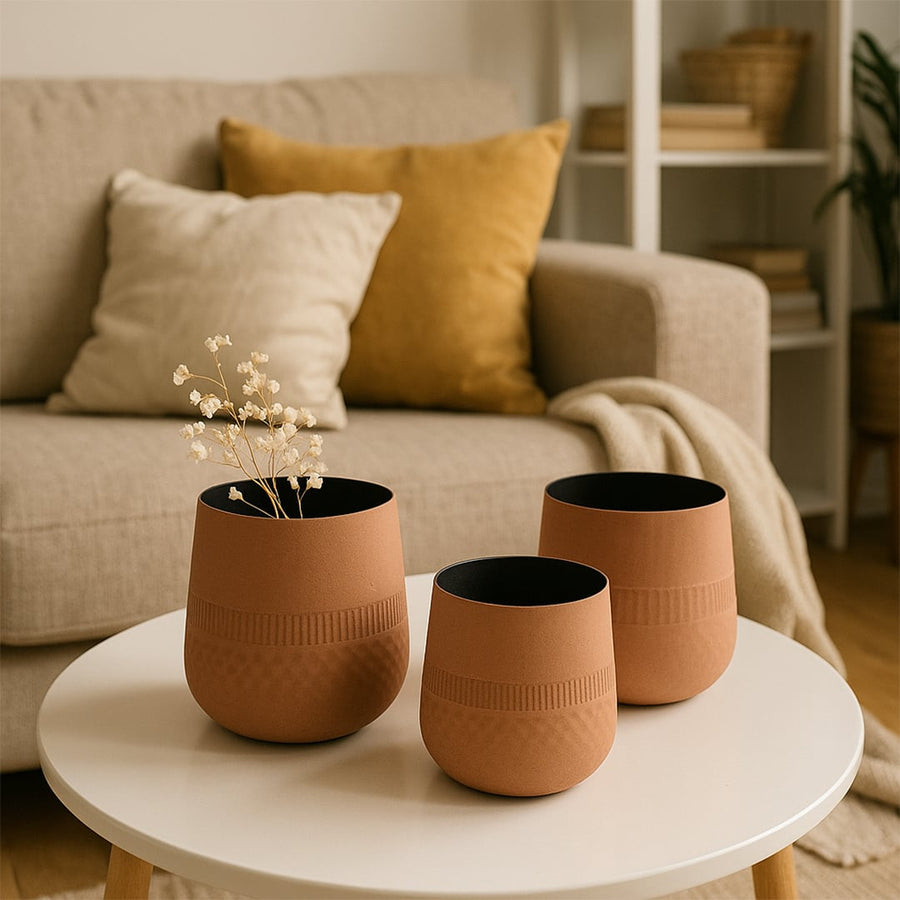 Terracotta textured pot with black interior styled with matching decor pieces creating a warm earthy modern lifestyle setting.