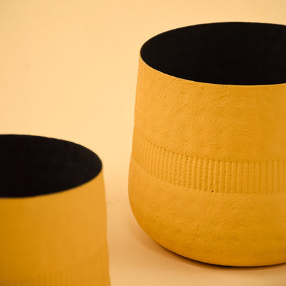 Closeup of yellow textured pot showing detailed ribbed pattern and matte black interior for stylish contemporary decor.