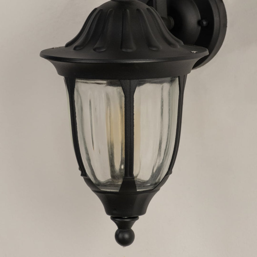 Close up shot focusing on the clear glass panels and the bulb socket inside the black metal cage of the wall light.