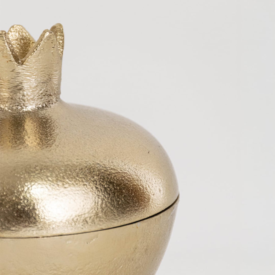 Closeup of gold pomegranate container highlighting crown lid and shiny metallic finish for elegant display accents