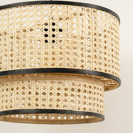 Layered cane pendant light with double drum design and black metal frame detail hanging against clean neutral wall background for contemporary decor.