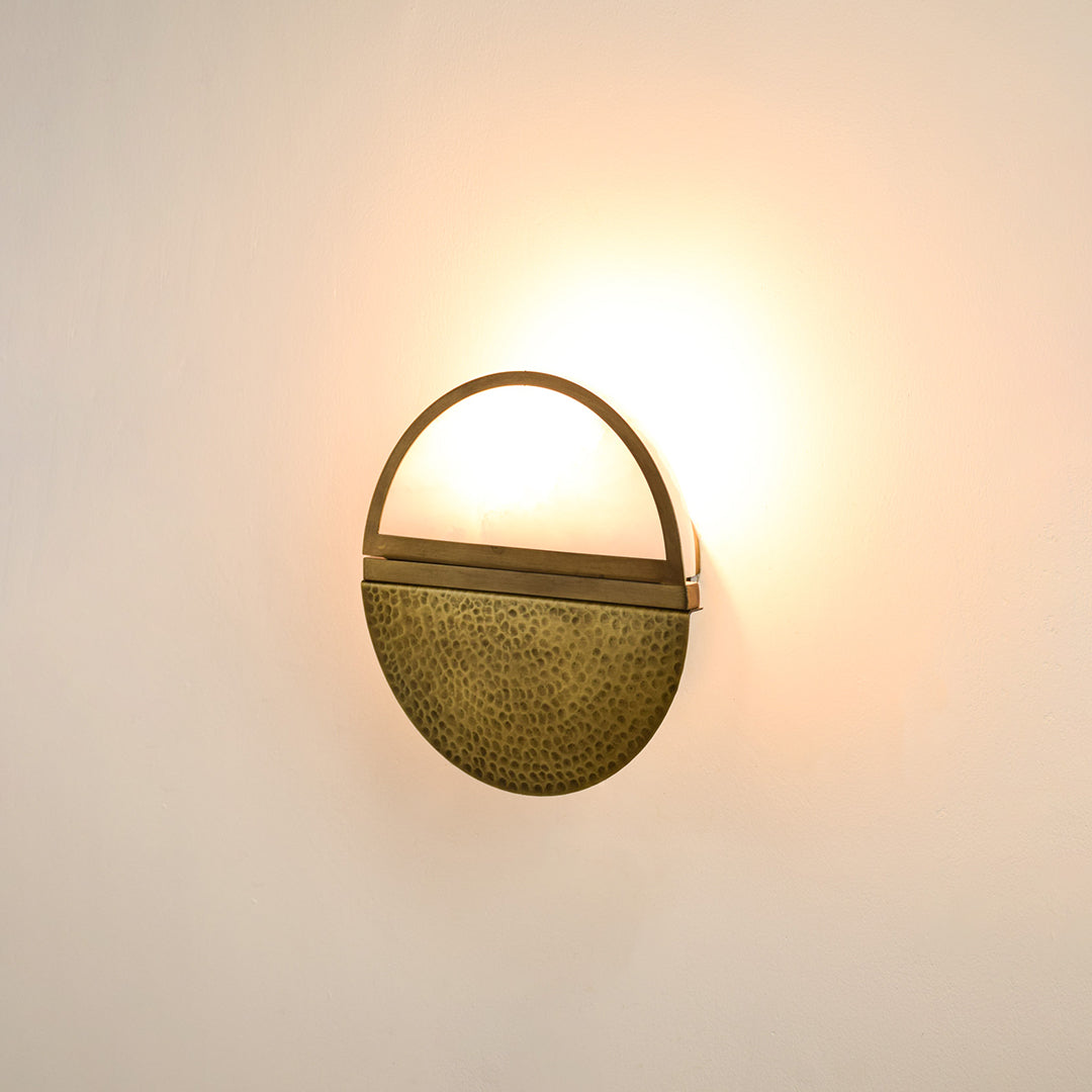 Modern gold metal wall light with warm ambient glow for stylish bedroom and luxury decor spaces.