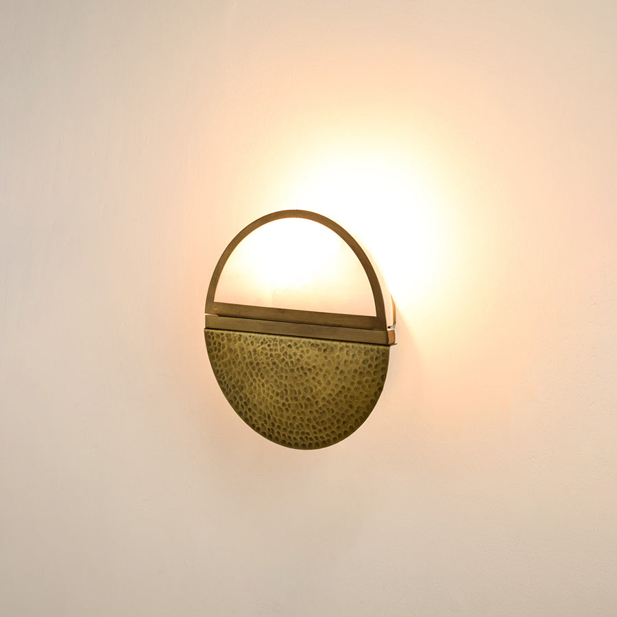 Modern gold metal wall light with warm ambient glow for stylish bedroom and luxury decor spaces.