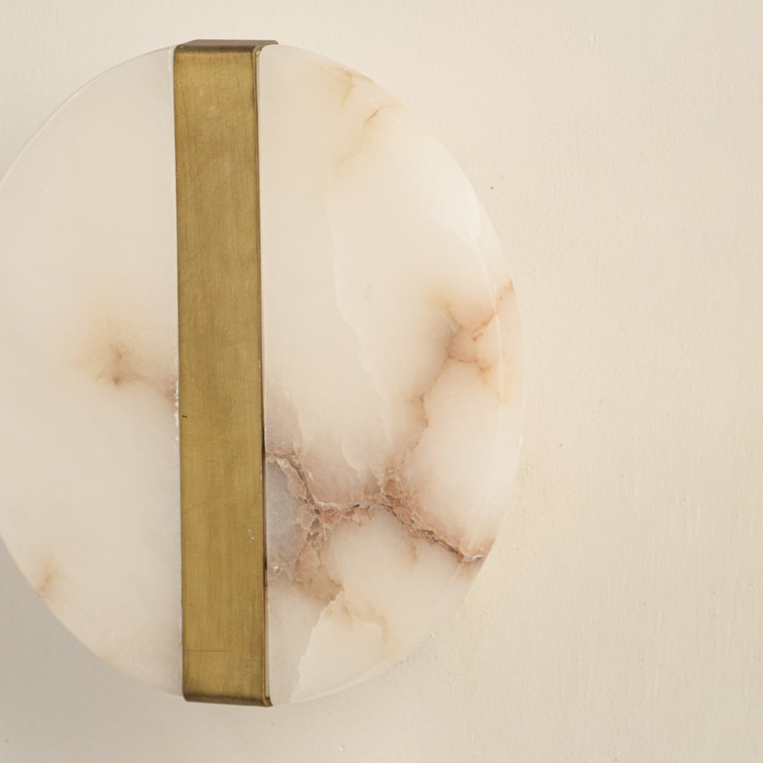 Closeup of marble and gold metal wall light for elegant hallway and luxury decor styling spaces.