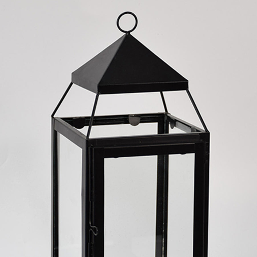 Closeup of black metal lantern with clear glass panels for modern tabletop decor styling use.