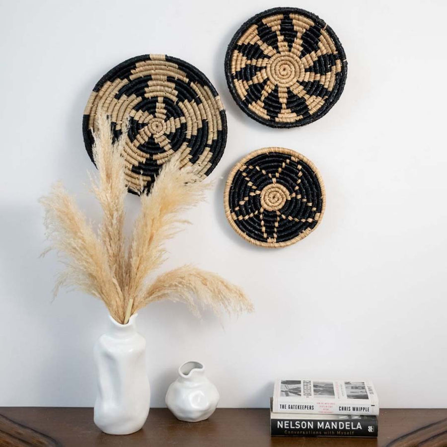Natural and black fiber wall basket decor displayed in artistic grouping above sideboard adding texture and warmth to living room wall.