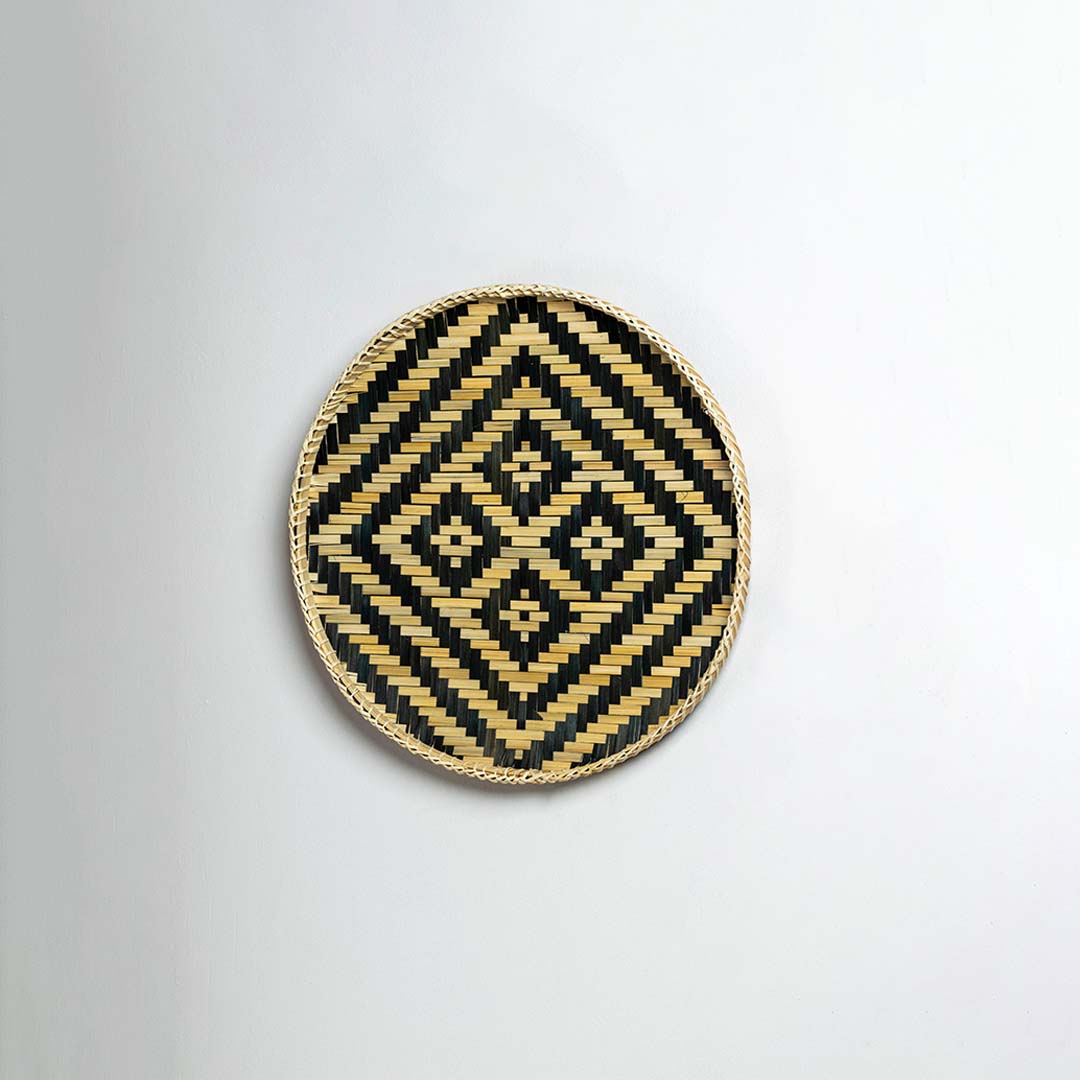 Side view of woven bamboo basket tray showing depth and handcrafted construction with black tribal geometric pattern detail.