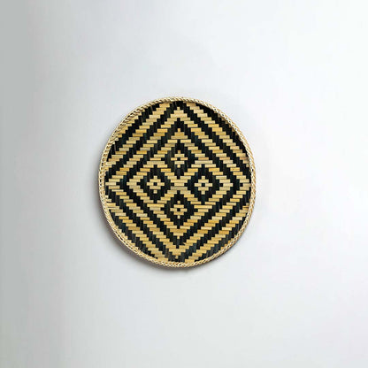 Side view of woven bamboo basket tray showing depth and handcrafted construction with black tribal geometric pattern detail.