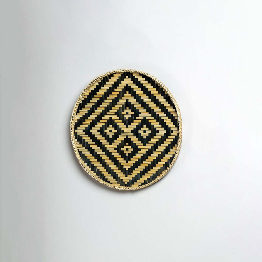 Side view of woven bamboo basket tray showing depth and handcrafted construction with black tribal geometric pattern detail.