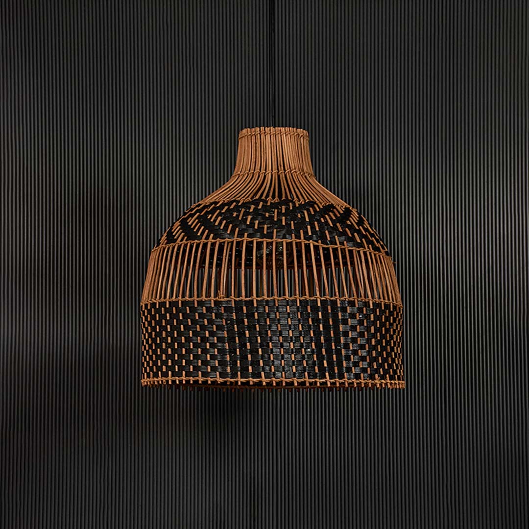 Two-tone rattan pendant light on dark background highlighting intricate weaving and smooth dome silhouette.