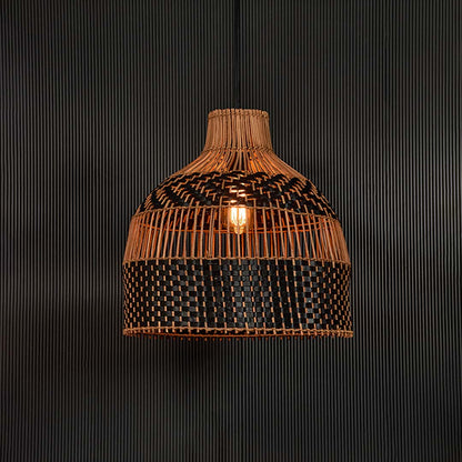 Rattan pendant light illuminated on black background creating warm ambience with refined handcrafted design.