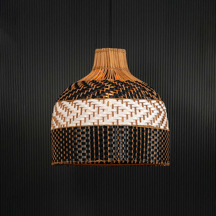 Rattan pendant light illuminated on dark background creating a warm glow through the artistic woven pattern.