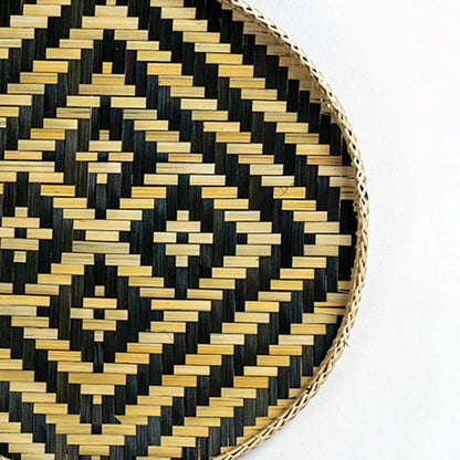 Closeup of handwoven wall basket edge with black and gold geometric weave highlighting natural fiber texture and artisan craftsmanship.