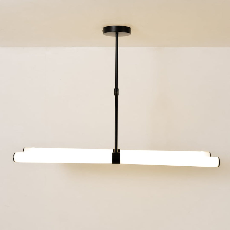 Warm-lit chandelier against a clean white background showcasing its modern linear design and suspended structure.
