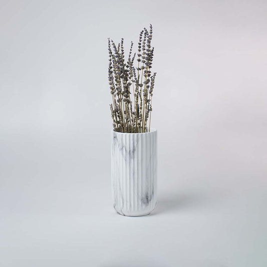 White ribbed ceramic vase with soft marble texture styled in a bright minimal setting giving a clean modern decorative look.